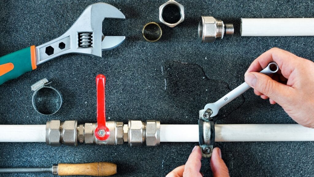 Plumber repairing a pipe valve with an adjustable wrench in Maitland