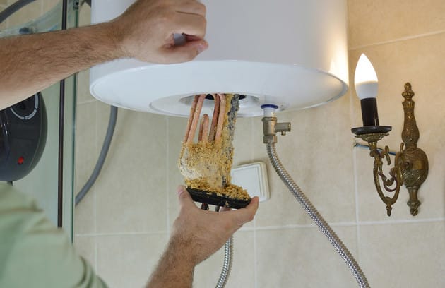 Technician removing mineral buildup from a water heater in Maitland