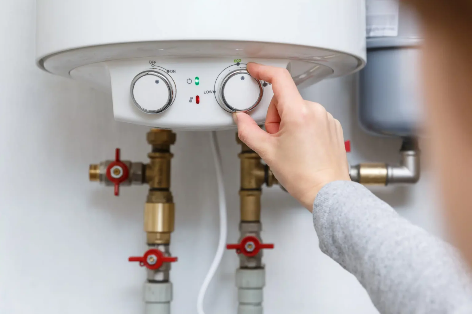 Homeowner adjusting the temperature controls on a water heater in Maitland